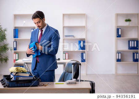 Young male employee preparing for trip at workplace Young male employee preparing for trip at workplace 94356191