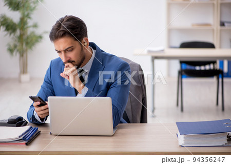 Deaf male employee using hearing aid at workplace 94356247