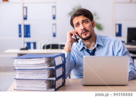 Young male employee and too much work in the office 94356888