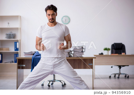 Young male employee doing sport exercises in the office Young male employee doing sport exercises in the office 94356910