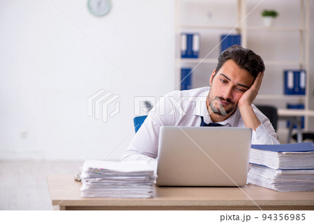 Young male employee unhappy with excessive work in the office 94356985