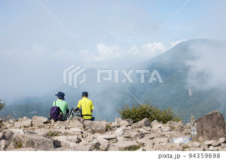 山頂で休憩するミドル登山者 94359698