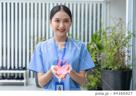 Asian Doctor holding pink ribbon smile positive emotional for supporting people to heal and fight to breast cancer. October breast cancer awareness month. Health care and insurance concept 94360927