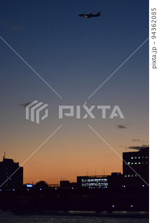 夕焼け空と月と飛行機 94362085