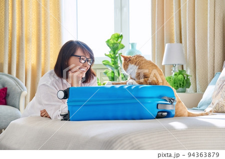 Happy woman packing suitcase with pet cat Happy woman packing suitcase with pet cat 94363879