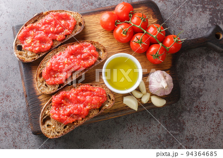 Catalan Pan con Tomate Spanish toasted bread rubbed with fresh garlic and ripe tomato, then drizzled with olive oil closeup on the wooden board. Horizontal top view 94364685