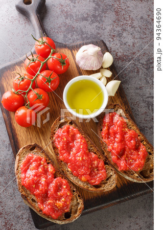 Spanish style toast with tomato Pan con tomate closeup on the wooden board. Vertical top view 94364690