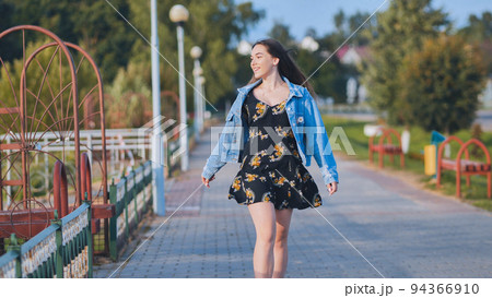 A cheerful girl walks along the city promenade. A cheerful girl walks along the city promenade. 94366910