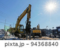解体工事現場の重機と輝く太陽 94368840
