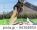 解体したコンクリートスラブを持ち上げる解体重機 94368850