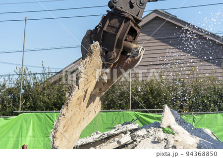 解体したコンクリートスラブを持ち上げる解体重機 94368850
