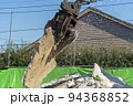 解体したコンクリートスラブを持ち上げる解体重機 94368852