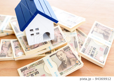 無造作に置かれた百万円の札束と家のオブジェ　不動産　住宅ローン　日本円 94369912