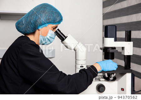 Female scientist looking at slides with patient samples using an inverted microscope in the laboratory. Female scientist looking at slides with patient samples using an inverted microscope in the laboratory. 94370562