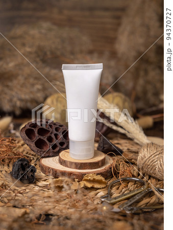 White plastic cream tube on wood near natural decorations closeup. Cosmetic packaging Mockup 94370727