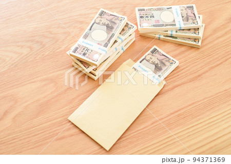 茶封筒に入った百万円の札束と積まれた札束　日本円 94371369