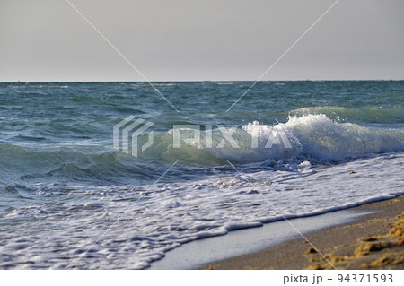 Seaside sand beach with foamy waves crushing on shore 94371593