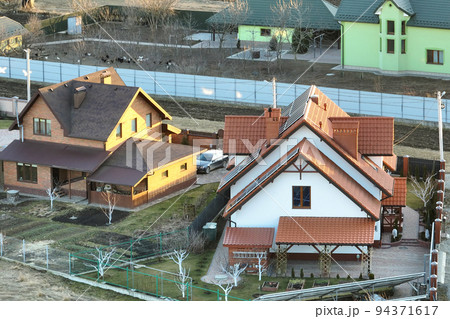 Residential houses with roof tops covered with metallic and ceramic shingles in rural suburban area 94371617