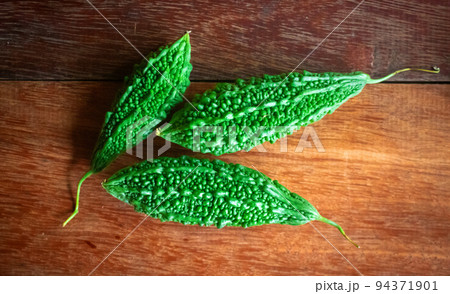 Wild bitter gourd on a wooden background. 94371901