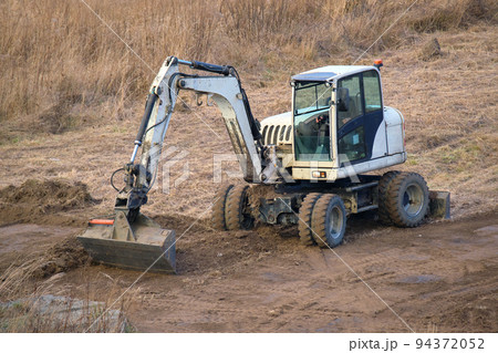 Earth moving tractor preparing place for future house foundation construction. Leveling soil for building new home 94372052