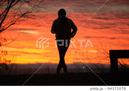 Dark silhouette of a lonely woman enjoying sunset view in evening nature. Loneliness and solitude concept Dark silhouette of a lonely woman enjoying sunset view in evening nature. Loneliness and solitude concept 94372078