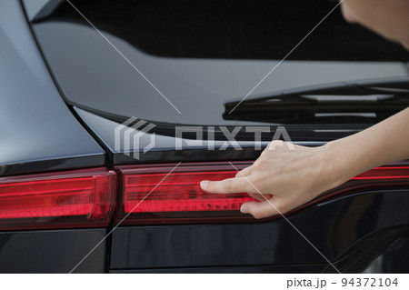 Close-up of human hand on rear car stoplight, checkout before driving. Safety travel concept Close-up of human hand on rear car stoplight, checkout before driving. Safety travel concept 94372104