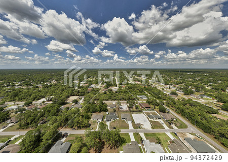 Aerial view of small town America suburban landscape with private homes between green palm trees in Florida quiet residential area Aerial view of small town America suburban landscape with private homes between green palm trees in Florida quiet residential area 94372429