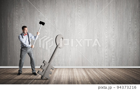 Breaking through access concept with man in room crashing concrete key Breaking through access concept with man in room crashing concrete key 94373216