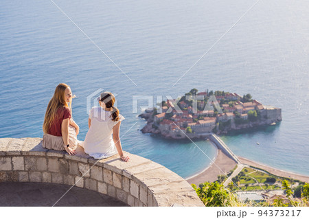 Two Woman tourist on background of beautiful view of the island of St. Stephen, Sveti Stefan on the Budva Riviera, Budva, Montenegro. Travel to Montenegro concept Portrait of a disgruntled girl Two Woman tourist on background of beautiful view of the island of St. Stephen, Sveti Stefan on the Budva Riviera, Budva, Montenegro. Travel to Montenegro concept Portrait of a disgruntled girl 94373217