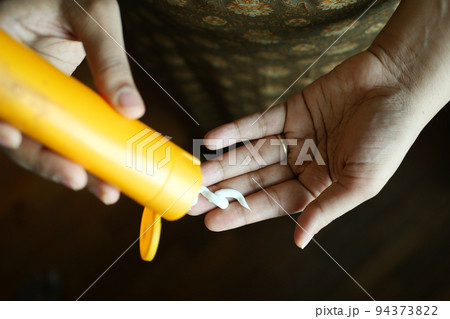 women hand applying sunscreen cream  94373822
