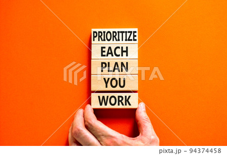 Prioritize each plan you work symbol. Concept words Prioritize each plan you work on blocks on beautiful orange background. Businessman hand. Business prioritize each plan you work concept. Copy space 94374458