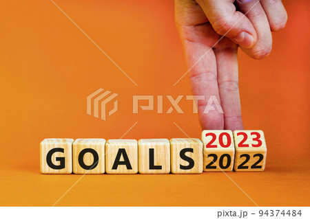 Planning 2023 goals new year symbol. Businessman turns a wooden cube and changes words Goals 2022 to Goals 2023. Beautiful orange background, copy space. Business 2023 goals new year concept. Planning 2023 goals new year symbol. Businessman turns a wooden cube and changes words Goals 2022 to Goals 2023. Beautiful orange background, copy space. Business 2023 goals new year concept. 94374484