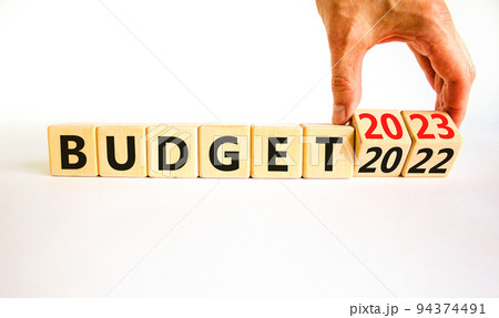 Planning 2023 budget new year symbol. Businessman turns a wooden cube and changes words Budget 2022 to Budget 2023. Beautiful white background, copy space. Business 2023 budget new year concept. 94374491