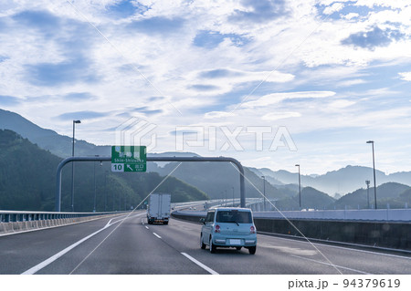 朝の新東名高速道路を走るトラックと乗用車　新静岡インターチェンジの出口を走行中 94379619