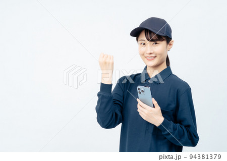 スマホを持つ配送業の女性(白バック、ガッツポーズ) スマホを持つ配送業の女性(白バック、ガッツポーズ) 94381379