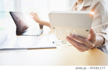 Business woman using calculator to review balance sheet annual with holding pen and using laptop computer to calculating budget. audit and Check integrity before investment concept Business woman using calculator to review balance sheet annual with holding pen and using laptop computer to calculating budget. audit and Check integrity before investment concept 94382177