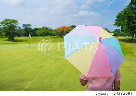 women Golfers under umbrella on green grass at golf course women Golfers under umbrella on green grass at golf course 94382693