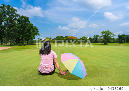 women Golfers under umbrella on green grass at golf course 94382694
