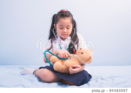 cute girls in medical uniform and stethoscope playing with a doll to be a doctor. child dreams of becoming a doctor career concept 94383097