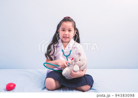 cute girls in medical uniform and stethoscope playing with a doll to be a doctor. child dreams of becoming a doctor career concept 94383098