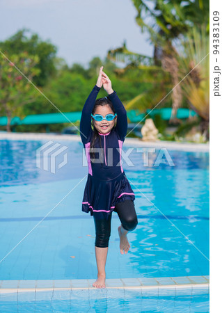 little girl smiling wearing swimming glasses in swimming pool. children playing in swimming pool on summer. 94383109
