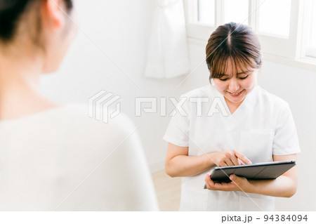 タブレットPCでカウンセリングする白衣の女性（看護師・カウンセラー・エステティシャン） 94384094