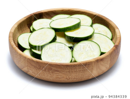 Sliced zucchini circles in wooden bowl isolated on white background Sliced zucchini circles in wooden bowl isolated on white background 94384339