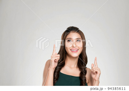Portrait of ardent woman looking at camera, finger pointing up for advertising. 94385611