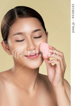 Closeup ardent woman applying her cheek with dry powder while looking at camera. 94386165