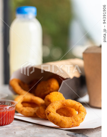 Crunchy deep fried squid or onion rings in batter set on gray stone table background. Co Crunchy deep fried squid or onion rings in batter set on gray stone table background. Co 94391906