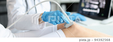 Doctor doing ultrasound examination of patient knee joint in clinic closeup 94392568