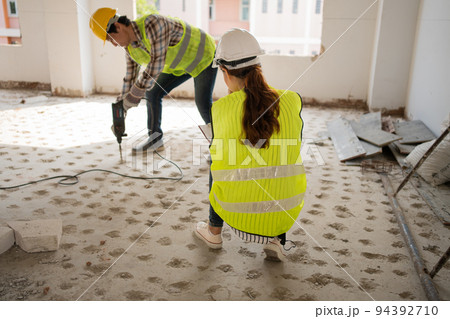 Engineer checking worker using an electric jackhammer to drill perforator equipment making holes before pouring the floor to be strong at construction site, Concept of worker and residential building Engineer checking worker using an electric jackhammer to drill perforator equipment making holes before pouring the floor to be strong at construction site, Concept of worker and residential building 94392710