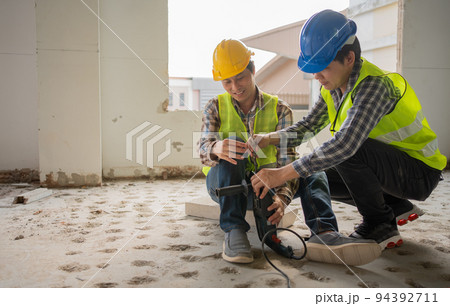 Engineer teaching worker for use electric jackhammer for perforator equipment making holes the floor to be strong at construction site, Concept of worker and residential building Engineer teaching worker for use electric jackhammer for perforator equipment making holes the floor to be strong at construction site, Concept of worker and residential building 94392711