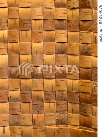 Wicker background from birch bark strips. Natural material. Texture of inner layers of birch bark of different colors with pattern of dark stripe 94394076